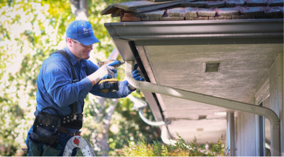 A technician installing a downspout to a gutter.