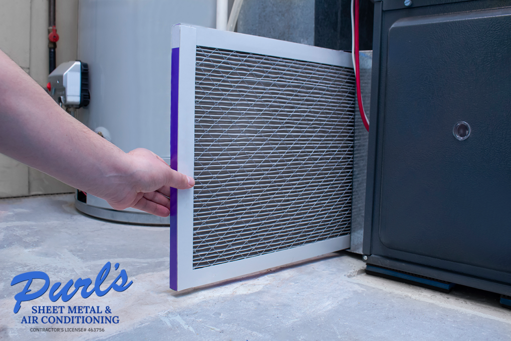 A person changing an air filter on a high efficiency furnace